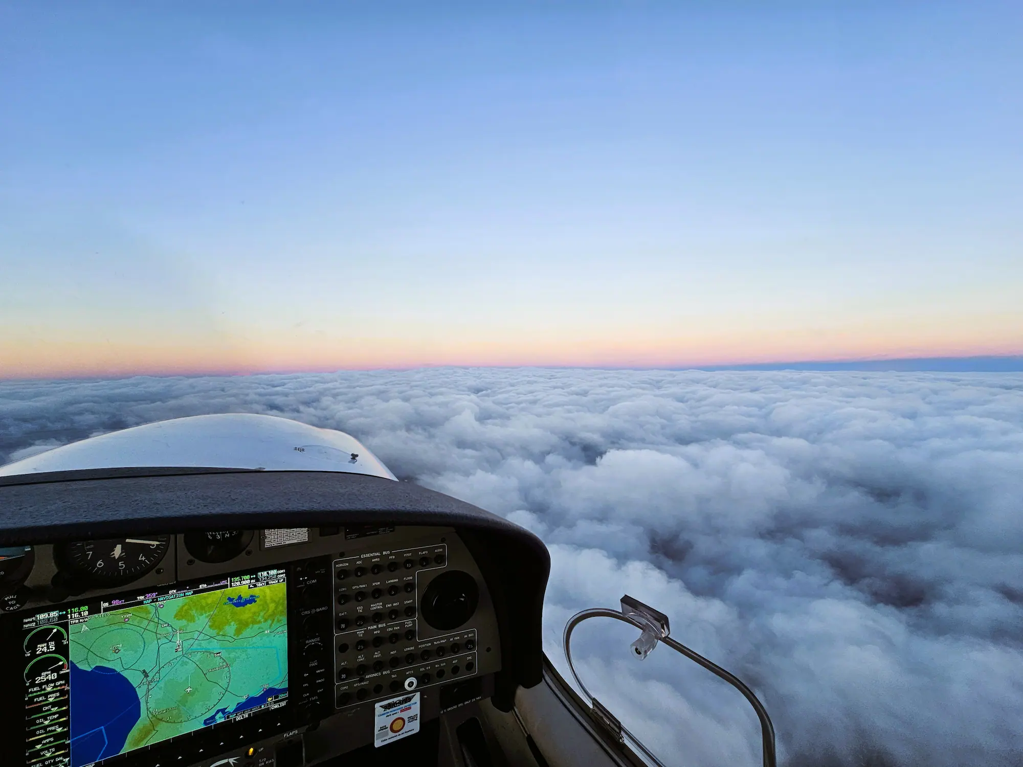 A training aircraft flying on top of the clouds at sunset